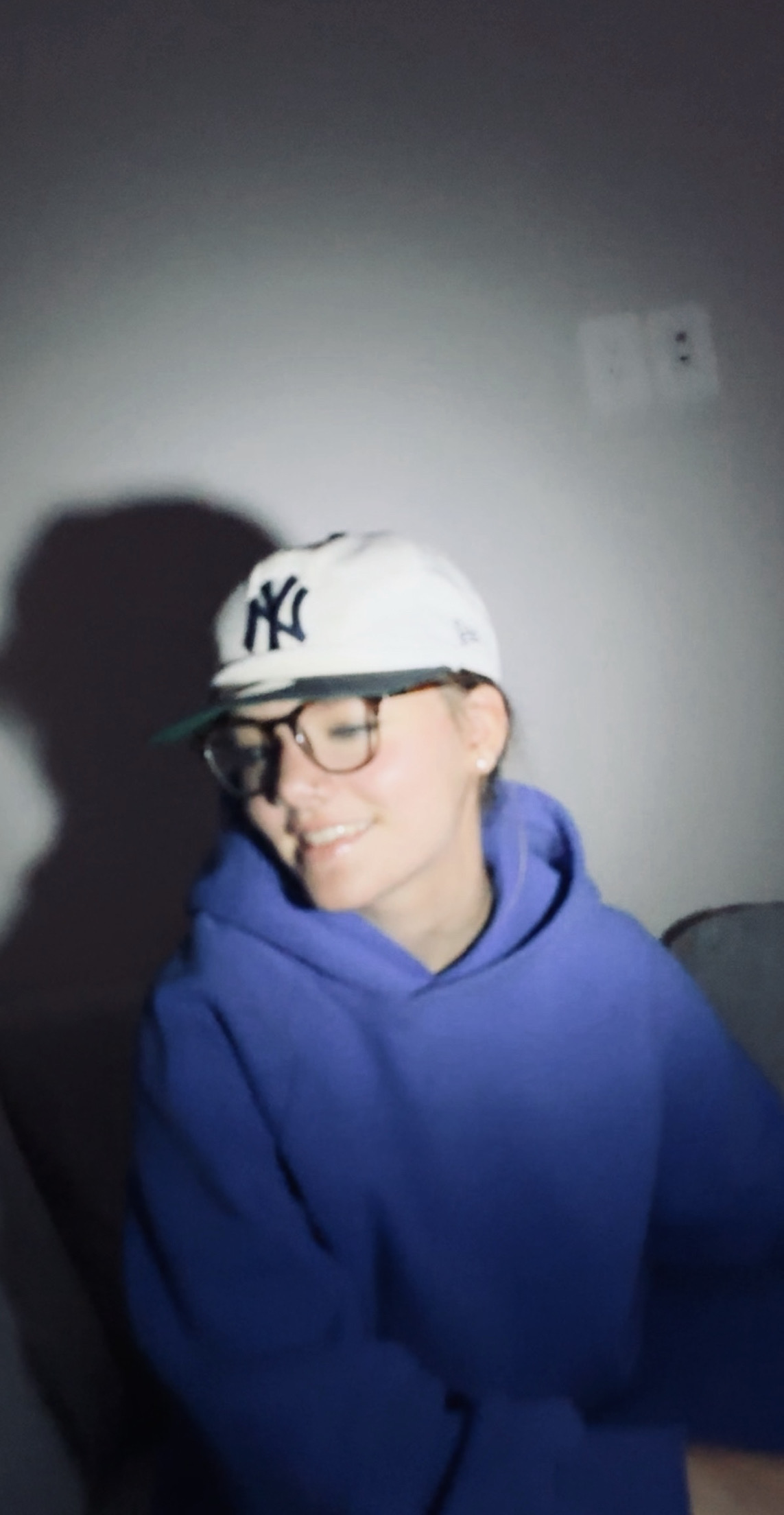 Macy Price wearing glasses, a white cap, and a blue hoodie